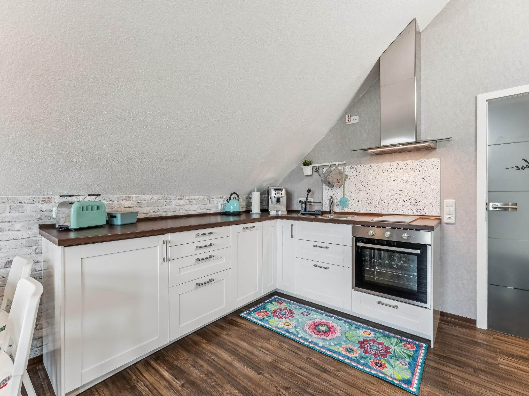 Une cuisine moderne avec des meubles blancs, un four en acier inoxydable et un plan de travail en bois.