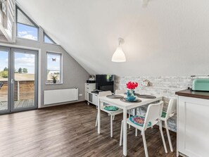 Eine moderne Küche mit Essbereich, Fernseher und Blick ins Freie.