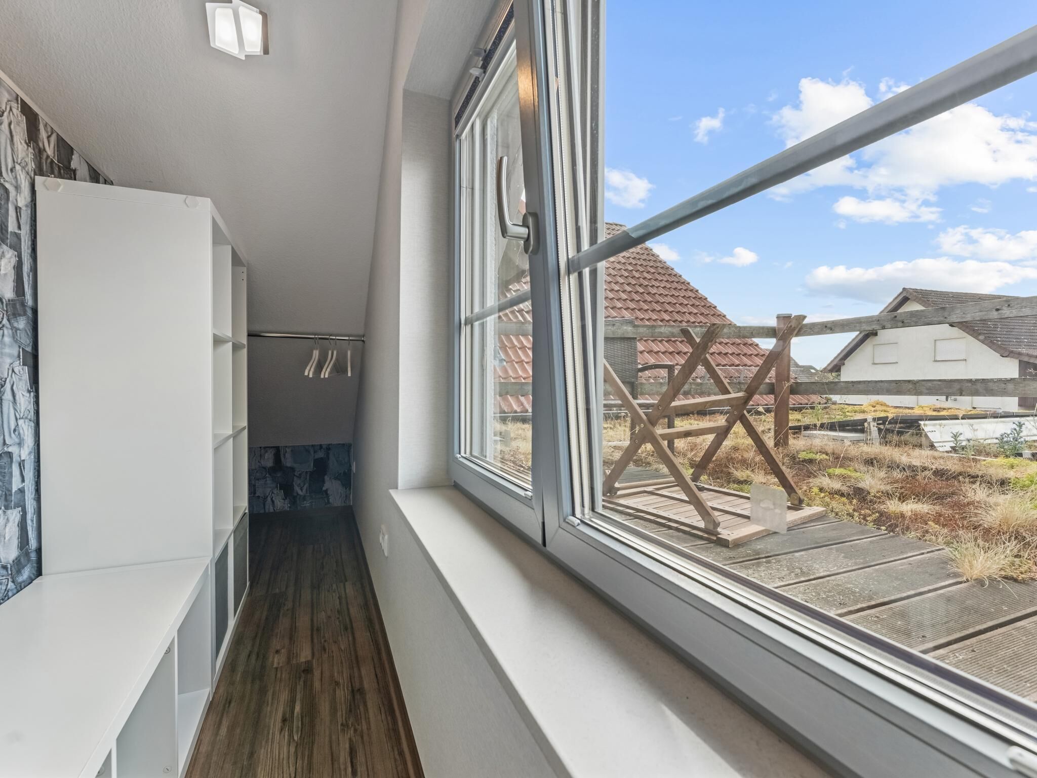 Un couloir étroit doté d’un plancher en bois et d’une grande fenêtre donnant sur un paysage rural.