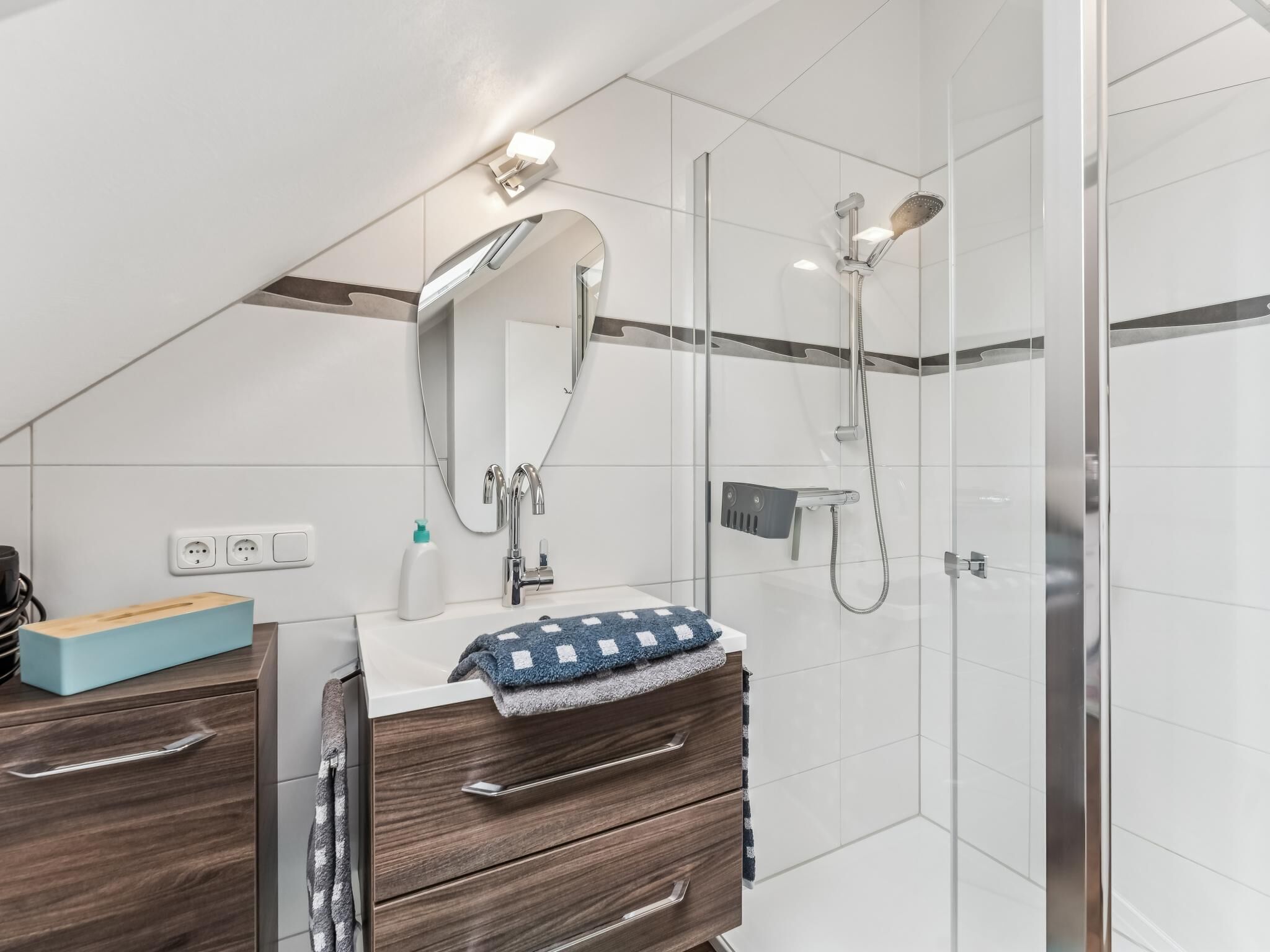 A modern bathroom with a shower, a sink, and a mirror.
