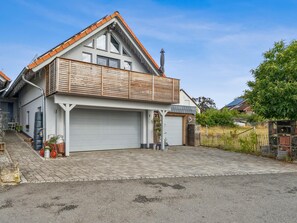 Ein zweistöckiges Haus mit Garage, Holzbalkon und befestigter Auffahrt.