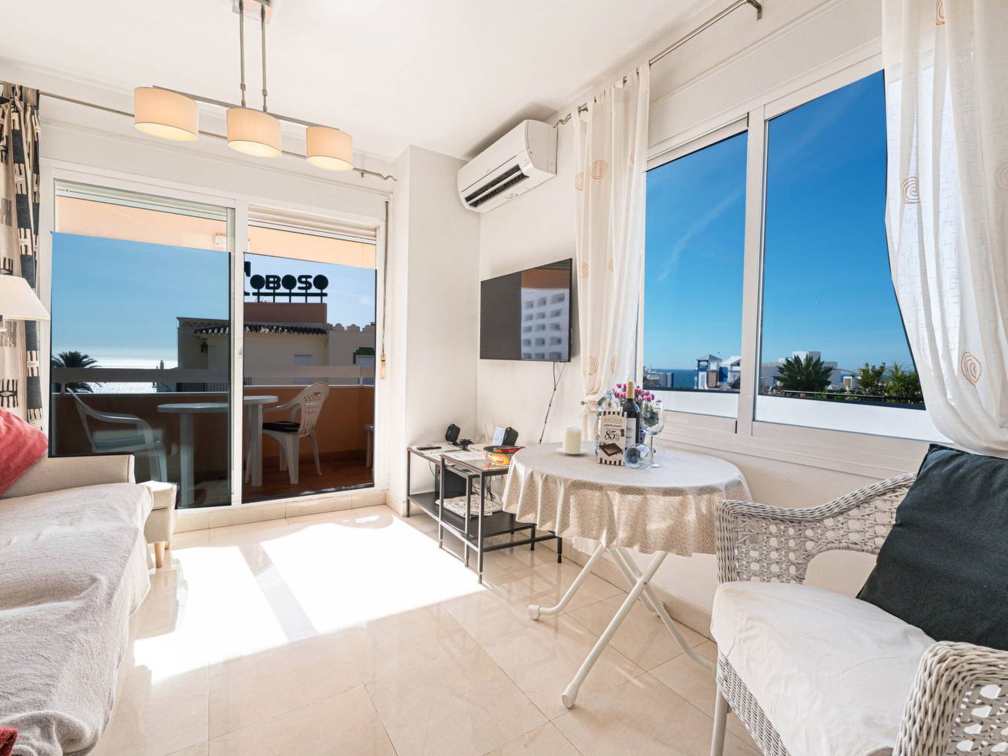 Une chambre d’hôtel avec un balcon, une table à manger, un canapé et une télévision.