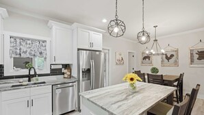 A modern kitchen with white cabinets, stainless steel appliances, and a marble countertop. - Big Ridge Hideaway Hot Tub (Talking Rock)