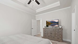 A bedroom with a bed, a dresser, a television on the wall, and a ceiling fan. - Big Ridge Hideaway Hot Tub (Talking Rock)