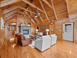 Ein rustikales Holzhaus-Interieur mit Kamin aus Stein, Ledermöbeln und einer Holzbalkendecke.