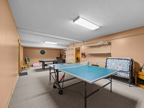 A room with a ping pong table, a green exercise ball, and a fire extinguisher on the wall. - Caribou Lodge at Lake Lure (Lake Lure)