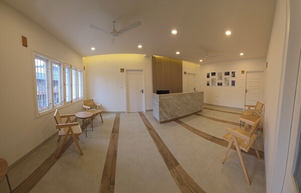 A reception area with a reception desk, seating area with chairs, and a ceiling fan.