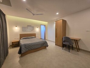 A modern bedroom with a bed, a desk, and a wardrobe. - Just Rooms (Chikkamagaluru)