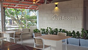 A cafe area with a 'JustRooms' sign, outdoor seating, and potted plants. - Just Rooms (Chikkamagaluru)