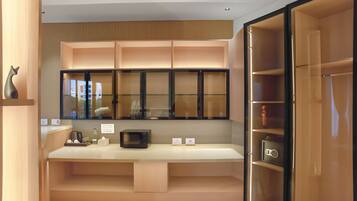 Una cocina moderna con microondas integrado, cafetera y refrigerador pequeño.