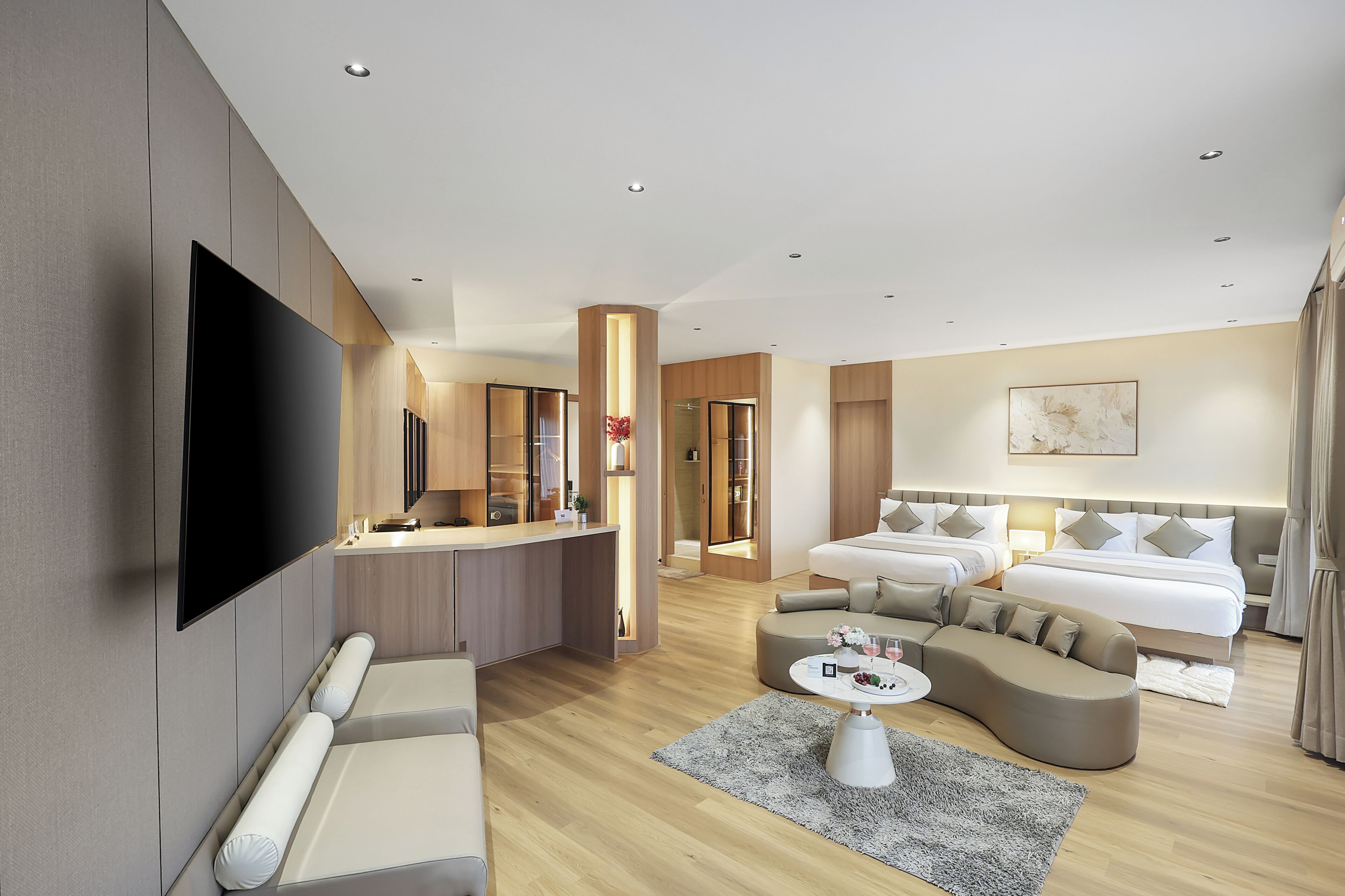 A modern hotel room with a flat-screen TV, a sofa, a bed, a desk, and a dining area.