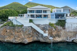 Ein modernes Haus, das auf einer felsigen Klippe thront, mit Pool und Terrassenmöbeln.