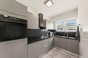 A modern kitchen with a built-in oven, a range hood, and a window with a view of the outside. - LagunBay Oceanfront Breeze (Lagun)