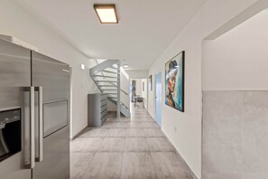 Una cocina moderna con electrodomésticos de acero inoxidable y una escalera que lleva a un comedor.