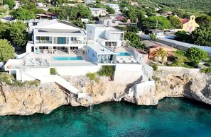 A coastal property with a pool, multiple balconies, and a cliffside location. - LagunBay  Oceanfront Pearle 2p (Lagun)