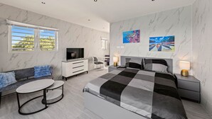 Ein modernes Schlafzimmer mit Bett, Fernseher, Sitzecke und Kunstwerken.
