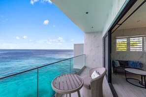 A balcony with a view of the ocean, a wicker table, and a sofa. - LagunBay  Oceanfront Pearle 2p (Lagun)
