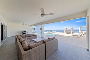 A spacious outdoor area with a large wicker sofa, a ceiling fan, and a view of the ocean. - LagunBay Oceanfront Horizon (Lagun)
