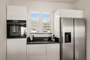 Eine moderne Küche mit Einbauofen, Kaffeemaschine und Kühlschrank.