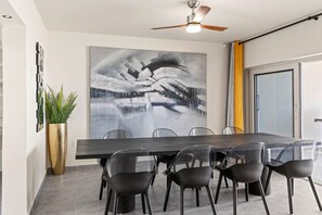 A dining area with a large abstract painting, a ceiling fan, and a potted plant. - LagunBay Oceanfront Horizon (Lagun)