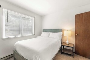 Una camera da letto con un letto, un comodino con una lampada e una porta.