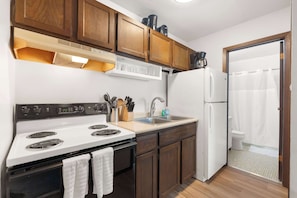 A compact kitchen with a stove, sink, and refrigerator. - Near UW Campus | Parking & Pet-Friendly (Madison)