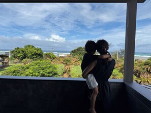Un balcón con vista al océano y al follaje.