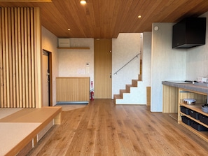 Un interior moderno con piso de madera, una escalera, una zona de cocina con estufa y un banco.