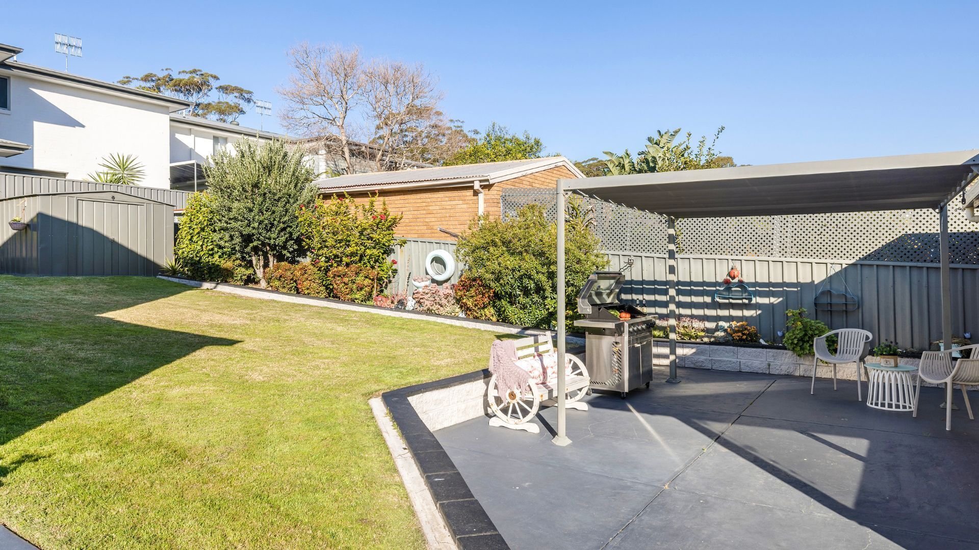 A backyard with a barbecue grill, outdoor seating, and a covered patio area.