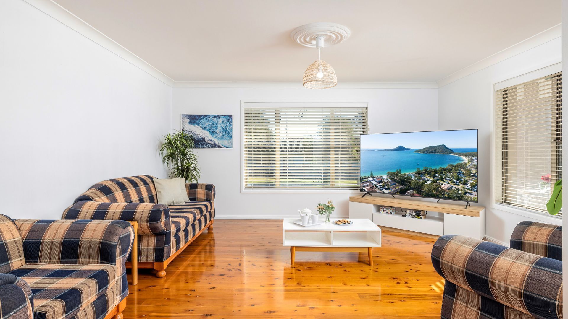 A living room with a sofa, coffee table, and a TV displaying a scenic view.