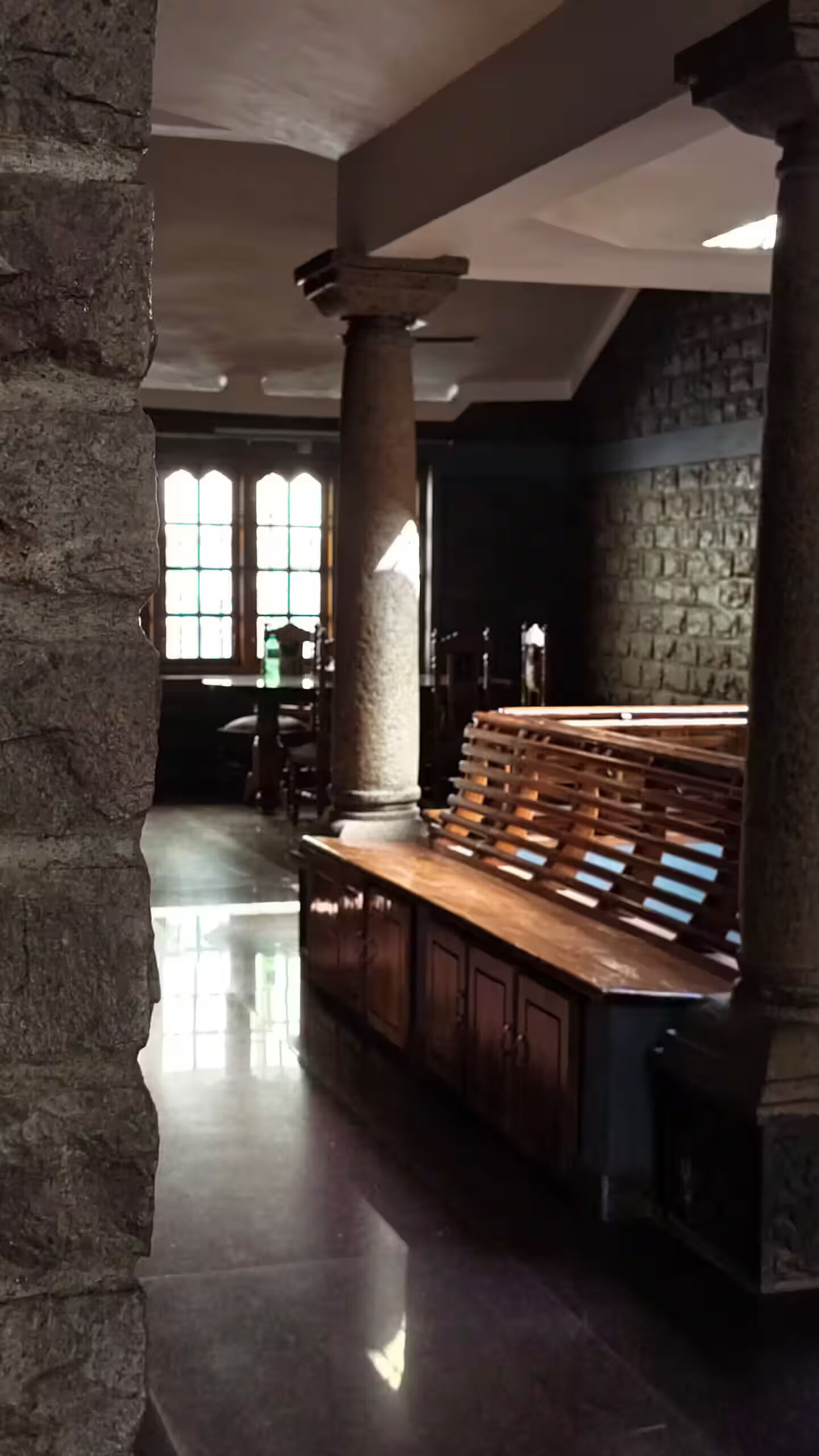 A spacious interior with a stone column, a wooden bench, and a stone wall.