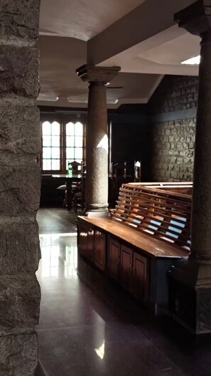 A spacious interior with a stone column, a wooden bench, and a stone wall.