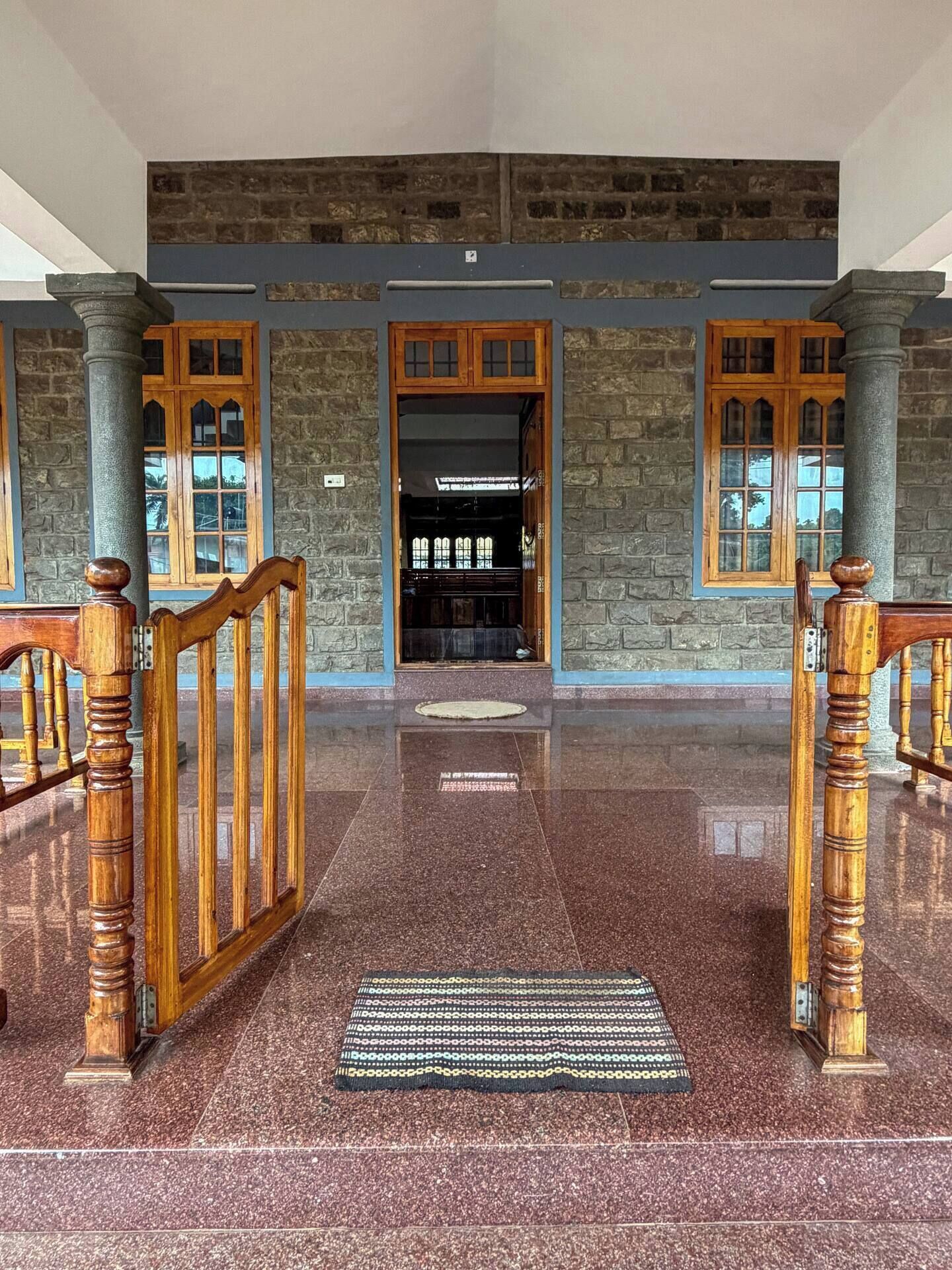 A spacious lobby with a polished floor, stone walls, and wooden doors.