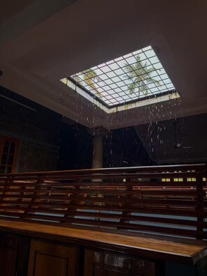 A room with a skylight, wooden bench, and a view of palm trees through the skylight.