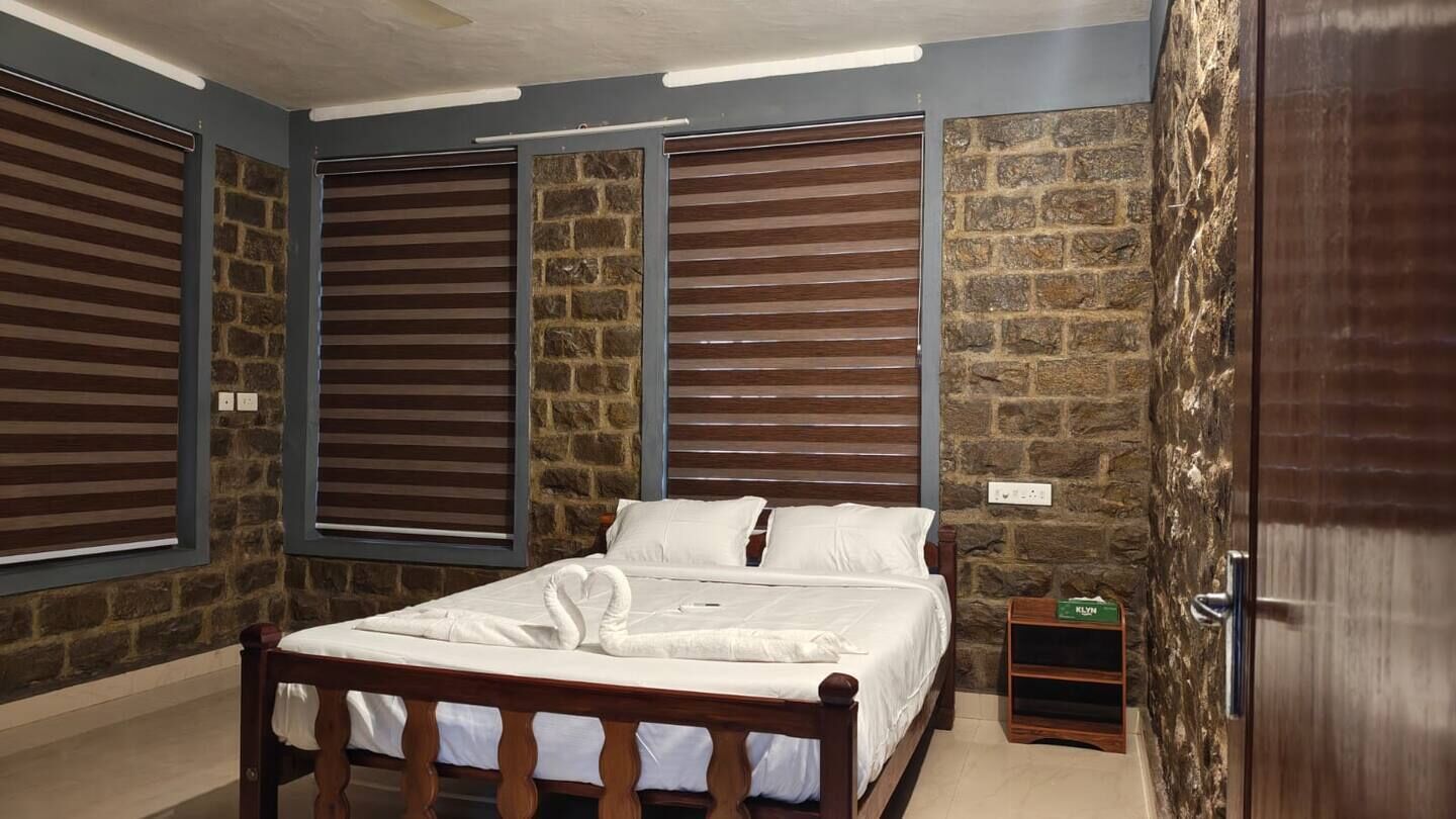 A bedroom with a wooden bed, stone walls, and a door.