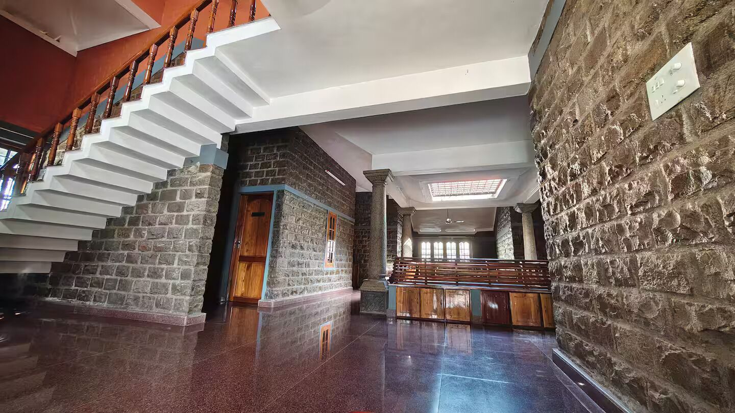Um interior amplo com escada, paredes de pedra e área de estar.