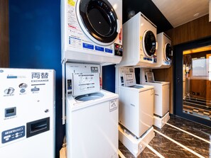 Un cuarto de lavandería con varias lavadoras y secadoras, un dispensador de agua y una máquina de cambio.