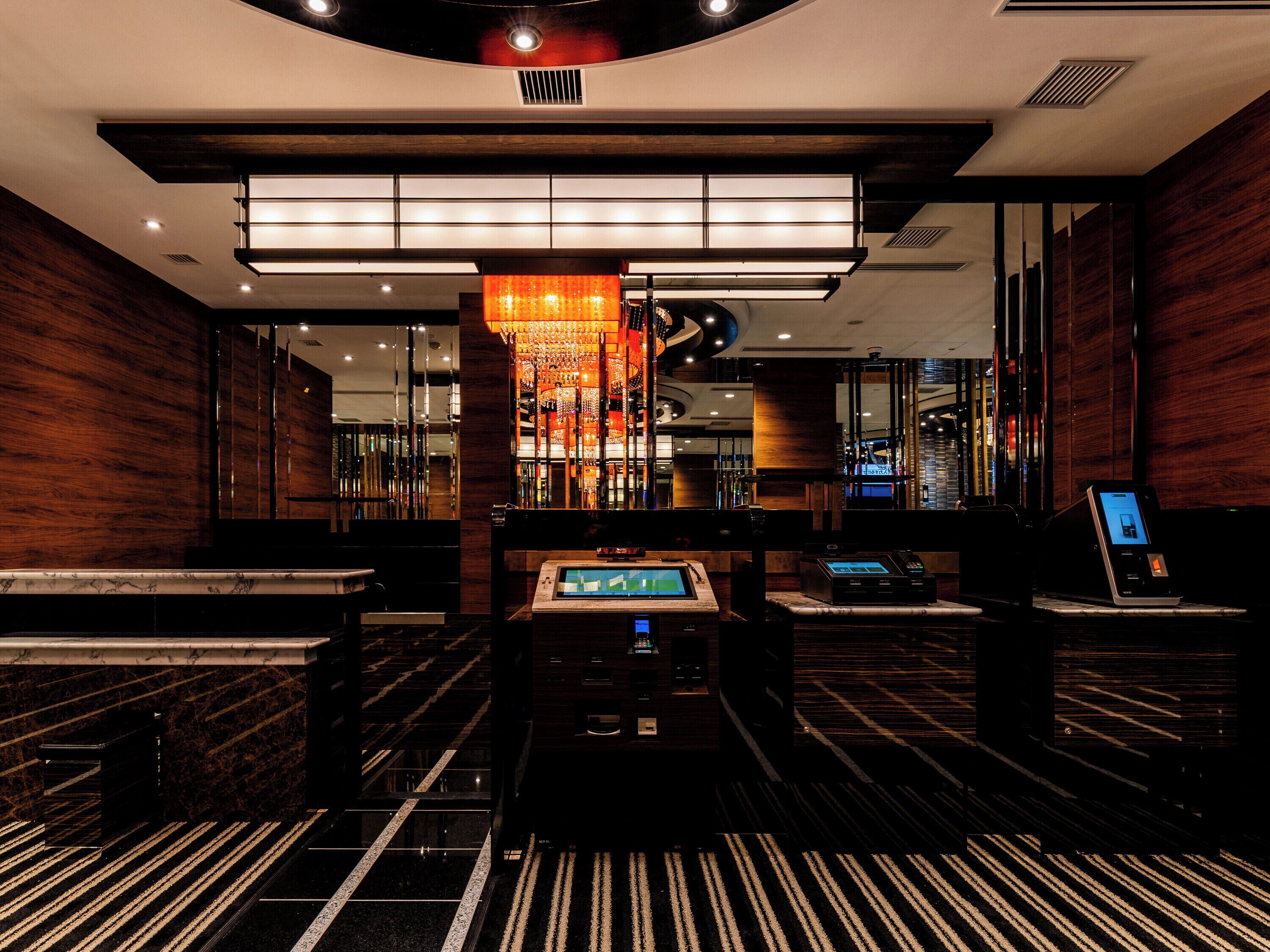 A hotel lobby with a reception desk, seating area, and a large chandelier.