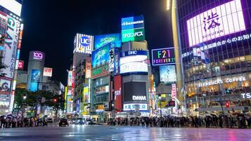 A busy urban street at night with illuminated billboards and storefronts.