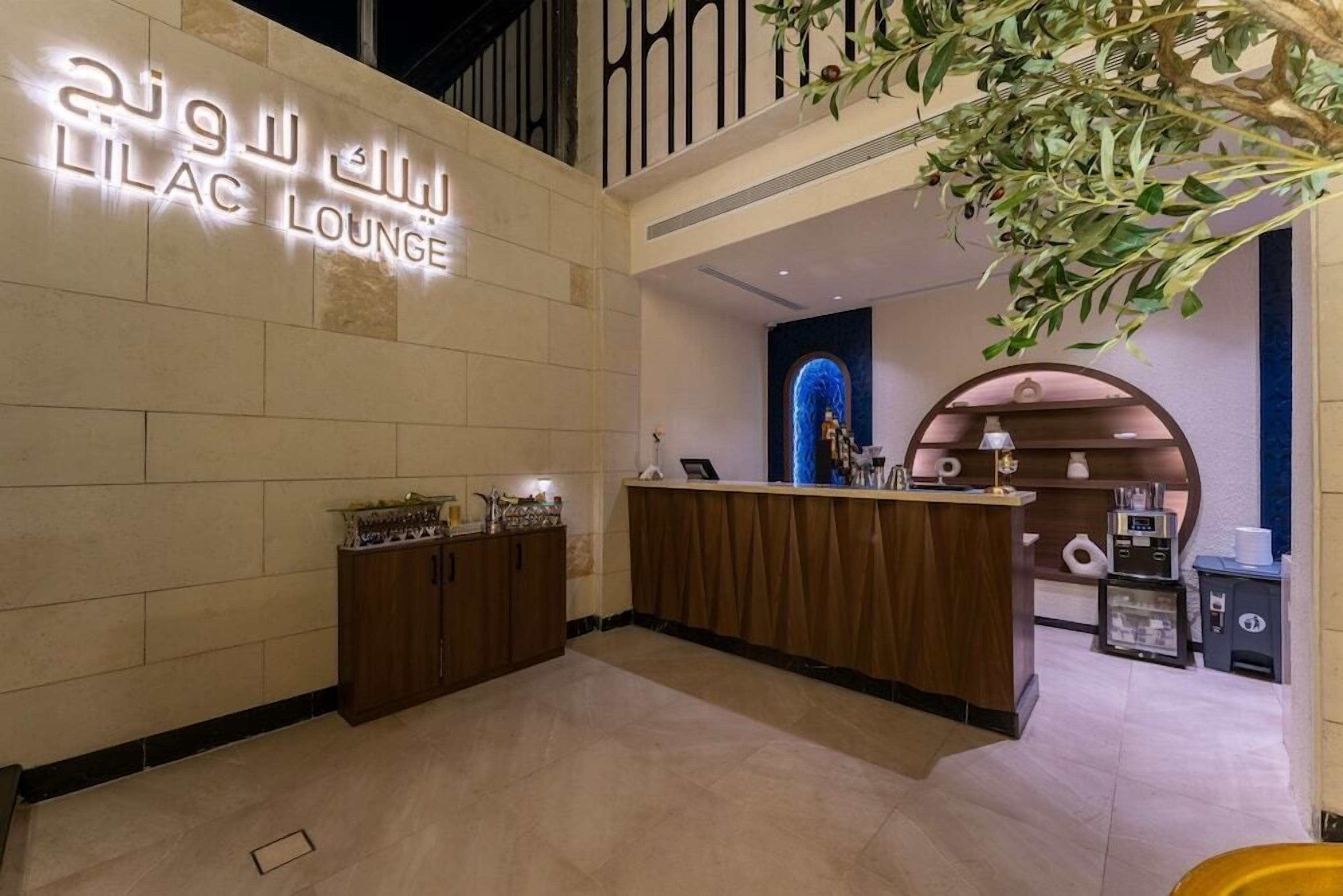 A reception area with a counter, a wall-mounted sign, and a decorative plant.