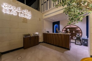 A reception area with a counter, a wall-mounted sign, and a decorative plant. - Lilac Park Neom Highway Hotel Ex Lilac Park Hotel (Tabuk)
