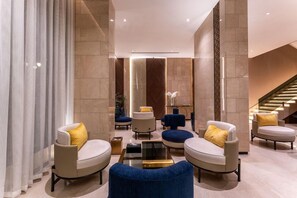 A modern lobby with a central seating area, a staircase, and a decorative wall.