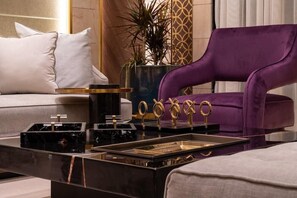 A modern living room with a purple sofa, a black marble coffee table, and a decorative plant.