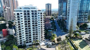 Un immeuble de grande hauteur doté de nombreux balcons, d’un court de tennis et entouré d’un paysage urbain.