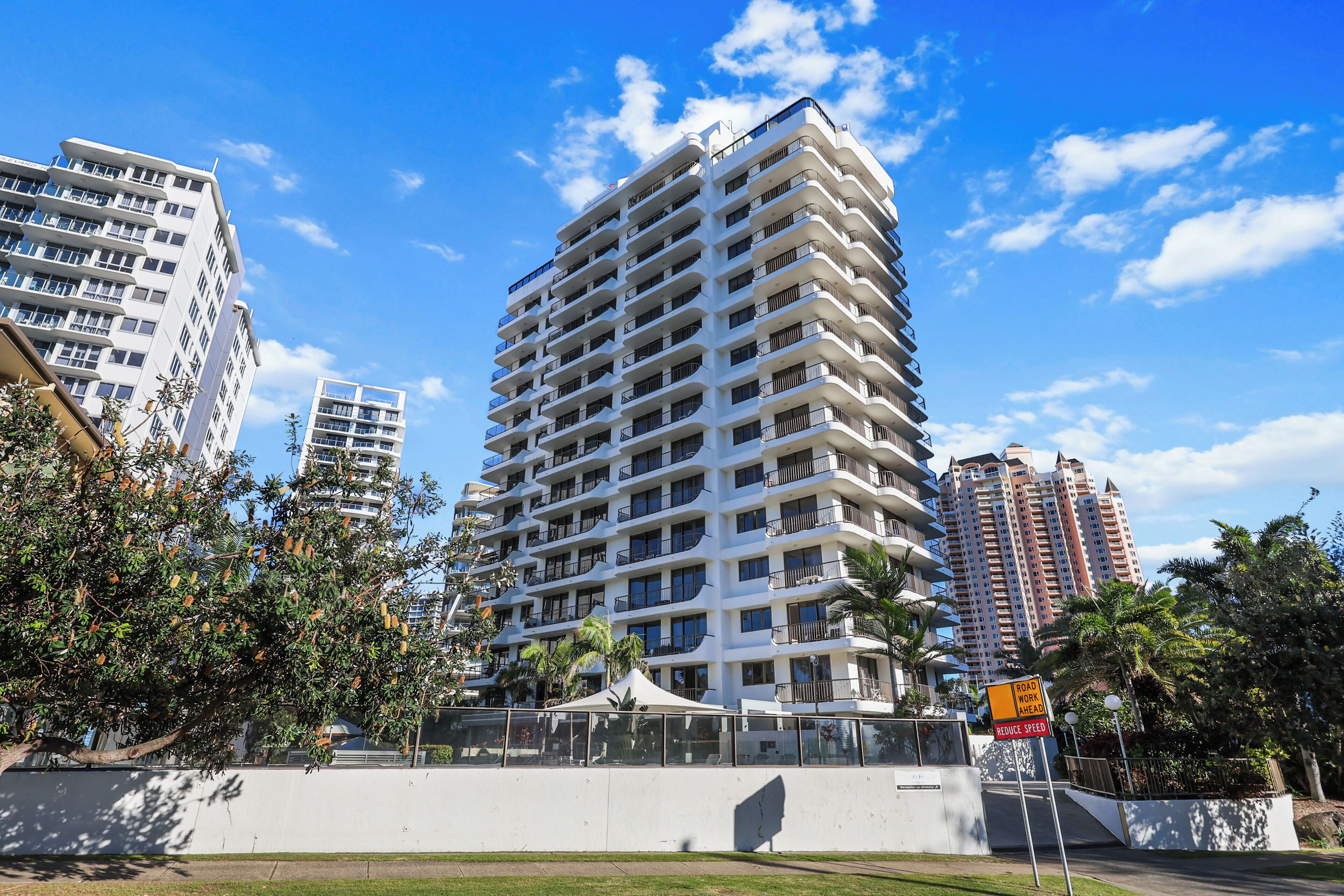 A high-rise building with multiple balconies and a clear sky.