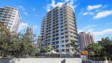 A high-rise building with multiple balconies and a clear sky.