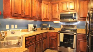 A kitchen with wooden cabinets, stainless steel appliances, a coffee maker, and a toaster.