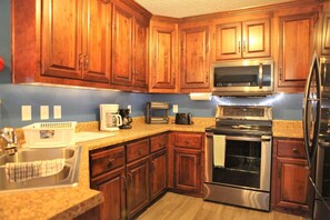A kitchen with wooden cabinets, stainless steel appliances, a coffee maker, and a toaster.