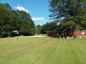 A grassy outdoor area with a covered structure and a red building.