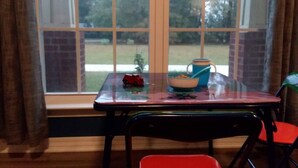 A room with a window, a table with a bowl and a toy car, and a chair.